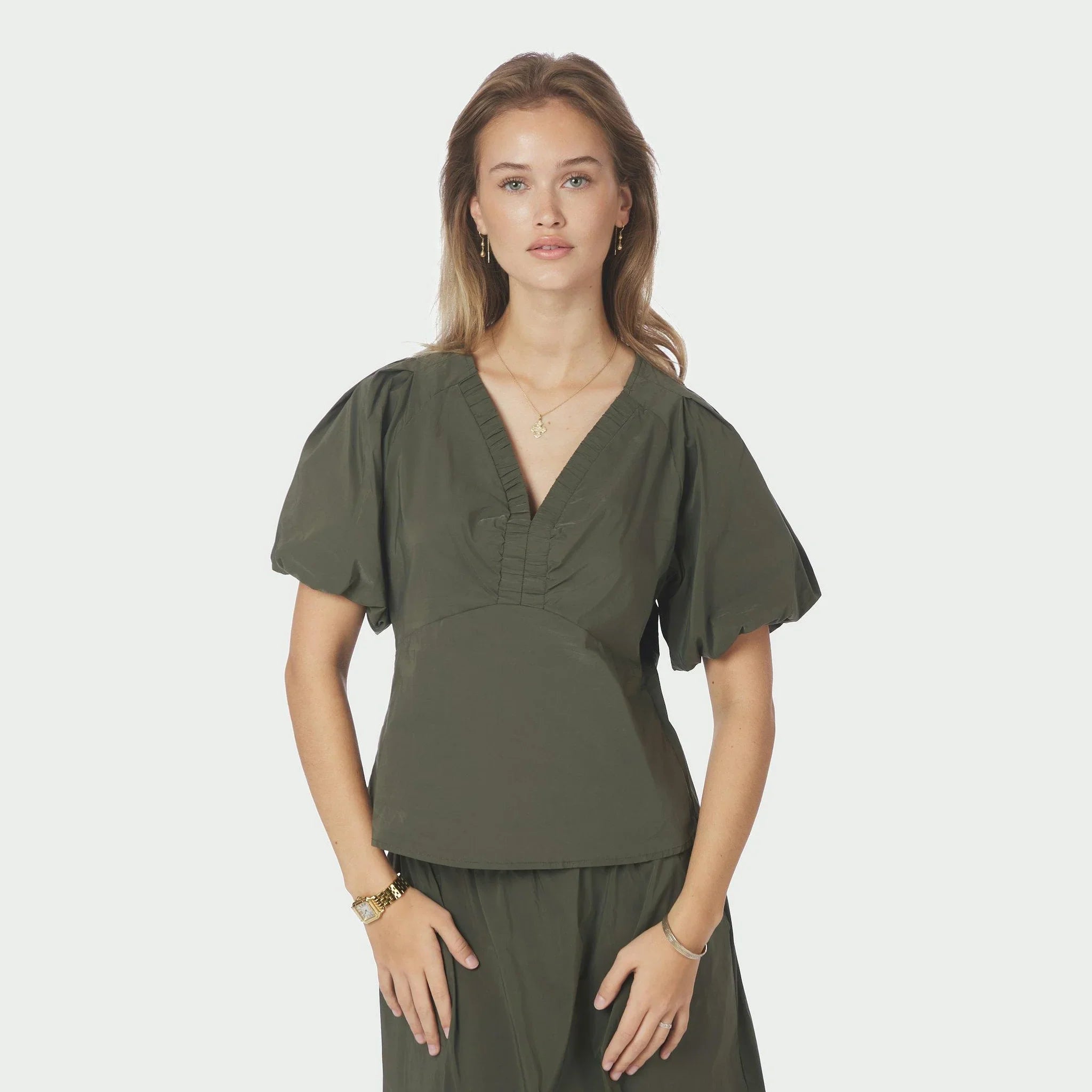 Model i grøn Irina bluse i farven Army med V-hals og rynkede kanter set forfra