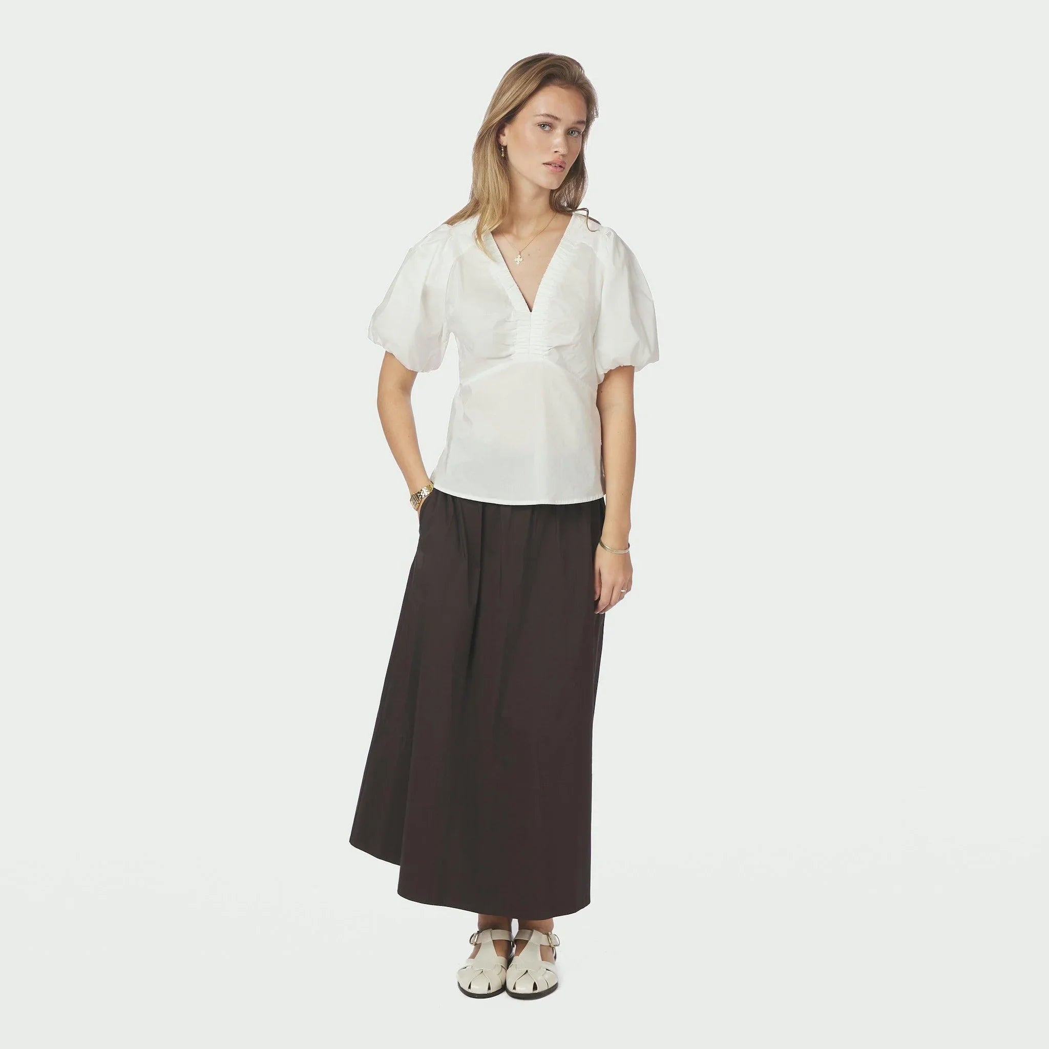 Model i hvid bluse fra Neo Noir i fuld figur, stylet med en lang mørk nederdel