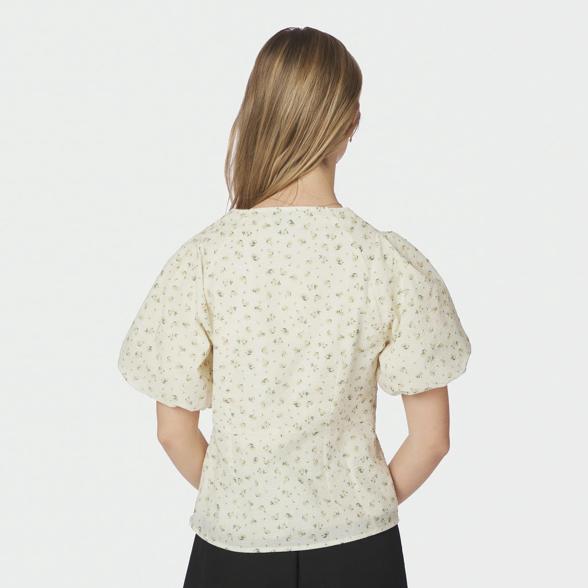 Model i lysegul blomstret bluse med puffede ærmer set bagfra