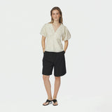 Model i fuld figur i lysegul blomstret bluse stylet med sorte shorts og sandaler