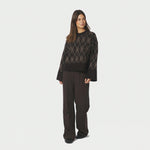 Model i brun argyle strikbluse stylet med brune bukser, fuld figur forfra