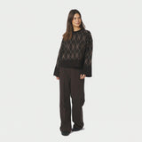 Model i brun argyle strikbluse stylet med brune bukser, fuld figur forfra