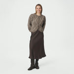 Model i fuld figur med beige ternet cardigan stylet med brun satinnederdel og støvler