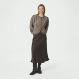 Model i fuld figur med beige ternet cardigan stylet med brun satinnederdel og støvler