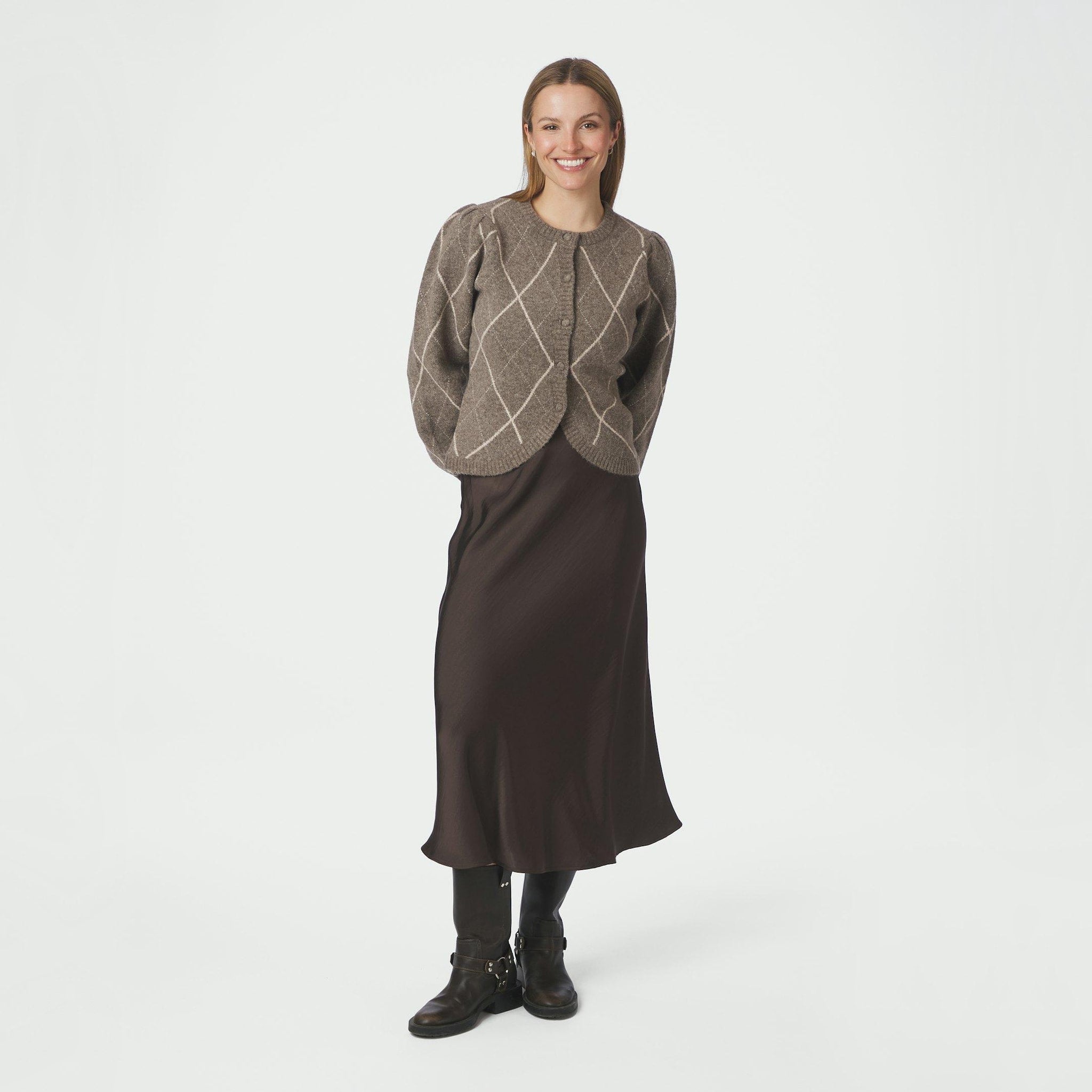 Model i fuld figur med beige ternet cardigan stylet med brun satinnederdel og støvler
