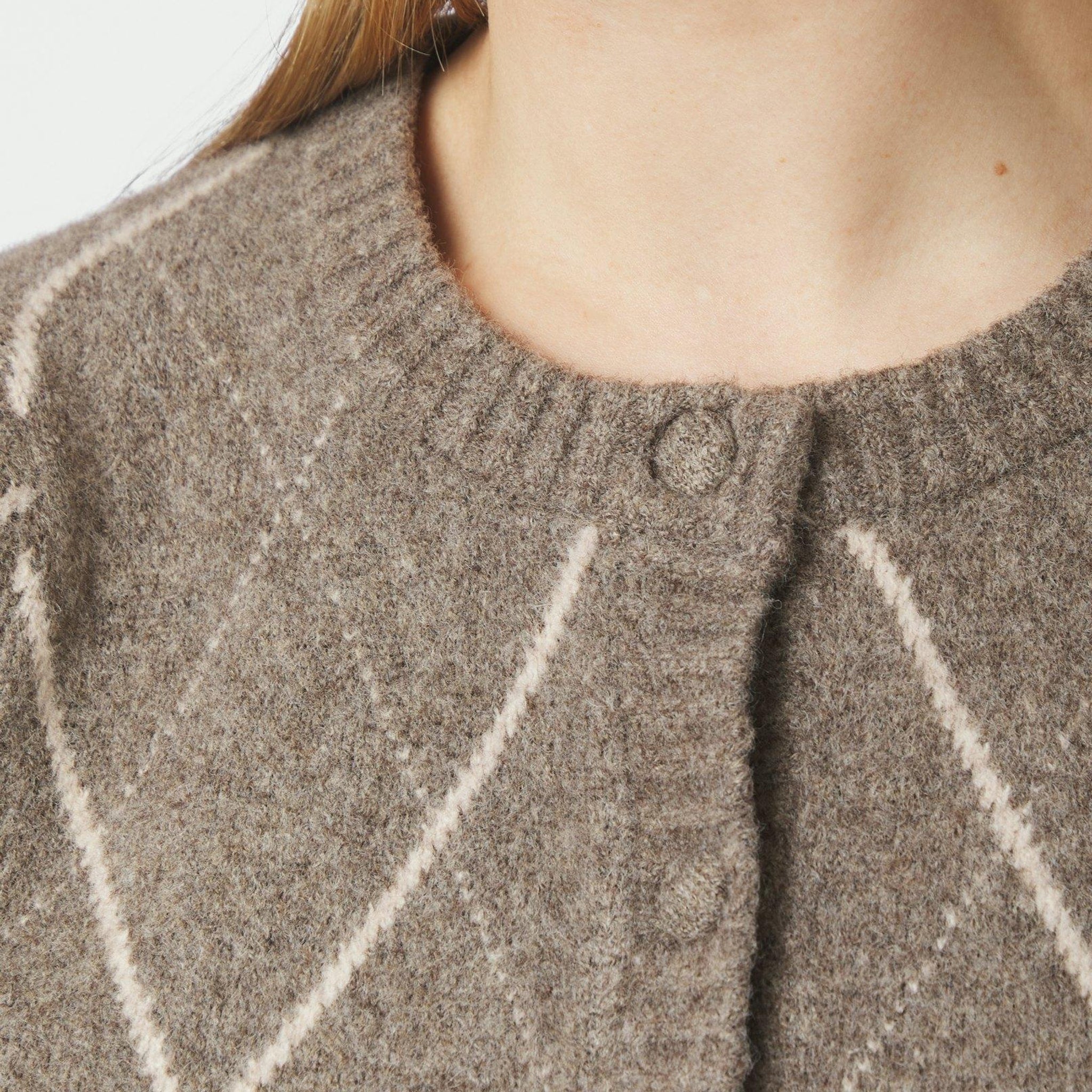 Nærbillede af rund hals med ribkant og knapper på beige ternet cardigan