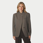 Model i brun pinstripe blazer med opstående krave og asymmetrisk lukning, tæt på forfra