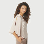 Model i beige satinbluse fra Neo Noir set fra siden med slids i det løse ærme