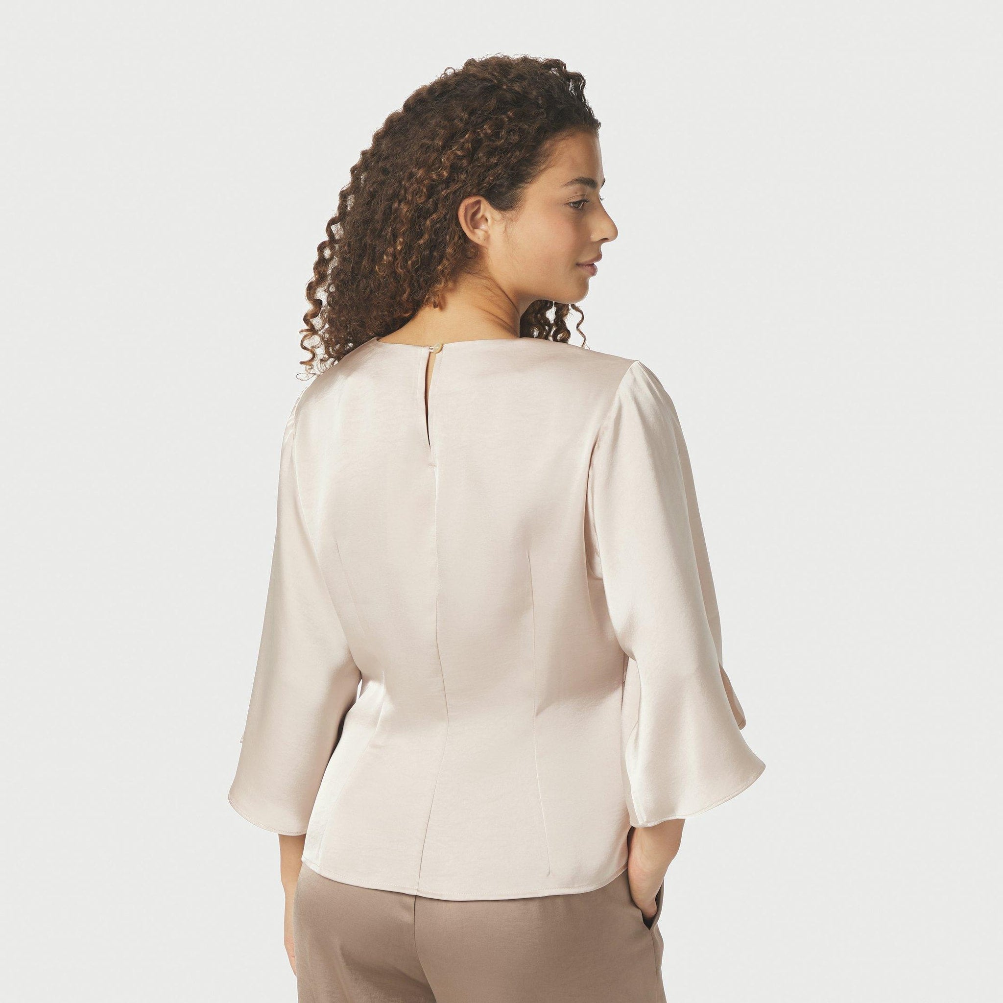 Model bagfra i beige Remana bluse i Champagne med knap i nakken