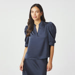 Model i navy bluse i satin med puffede ærmer og åbning foran, set forfra