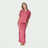 Model i hel figur i pink satinbluse Roella stylet med lang satinnederdel i samme farve
