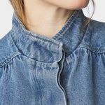 Nærbillede af den høje hals og skjulte lukning på blå denimjakke