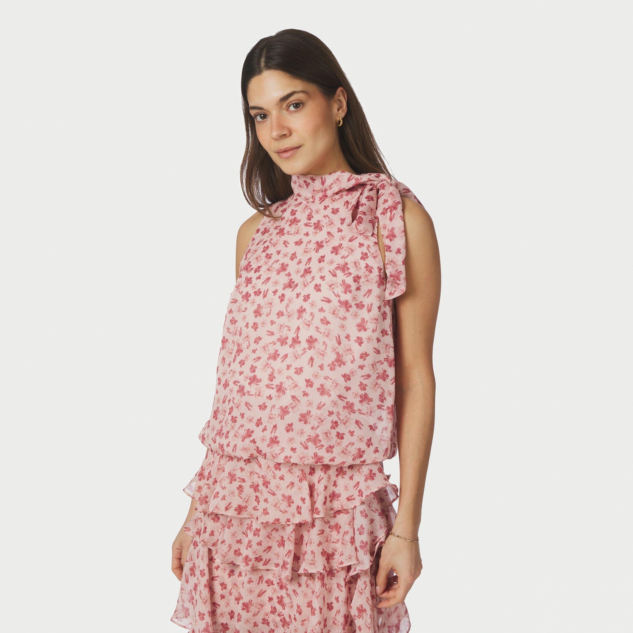 Model i pink halterneck-top med blomsterprint og sløjfe ved skulderen