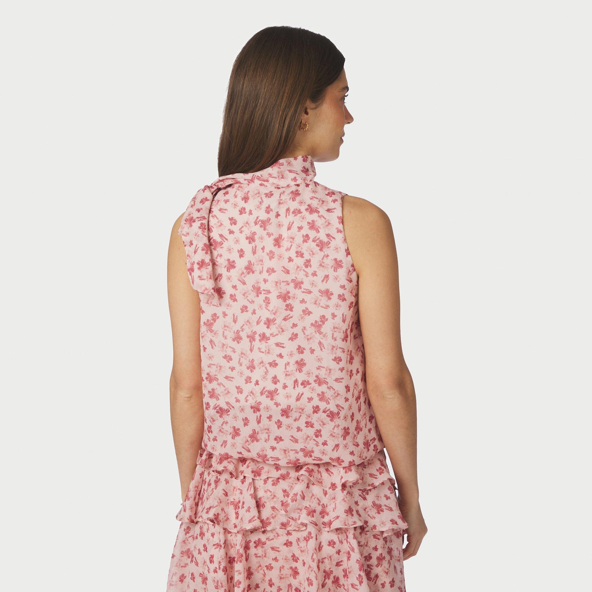 Model i pink top med blomsterprint set bagfra med sløjfebånd over skulderen