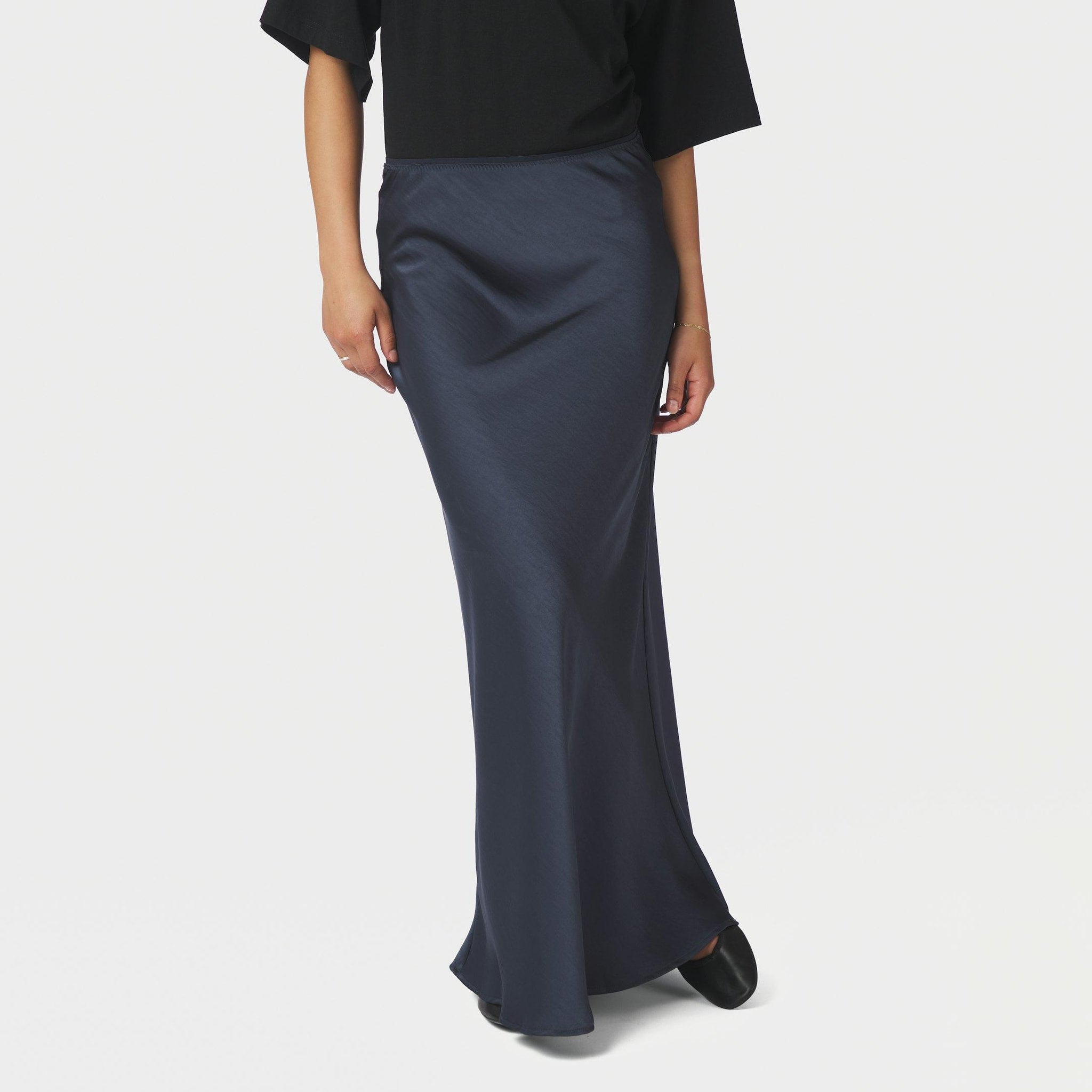 Model i lang navy nederdel i satin set forfra, stylet med sort t-shirt