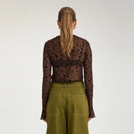 Model i brun mesh t-shirt med sorte prikker set bagfra