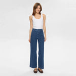 Model i blå jeans med høj talje og brede ben set forfra, hånd langs siden