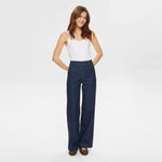 Smilende model i blå wide leg jeans med høj talje fra Nümph og hvid top set forfra