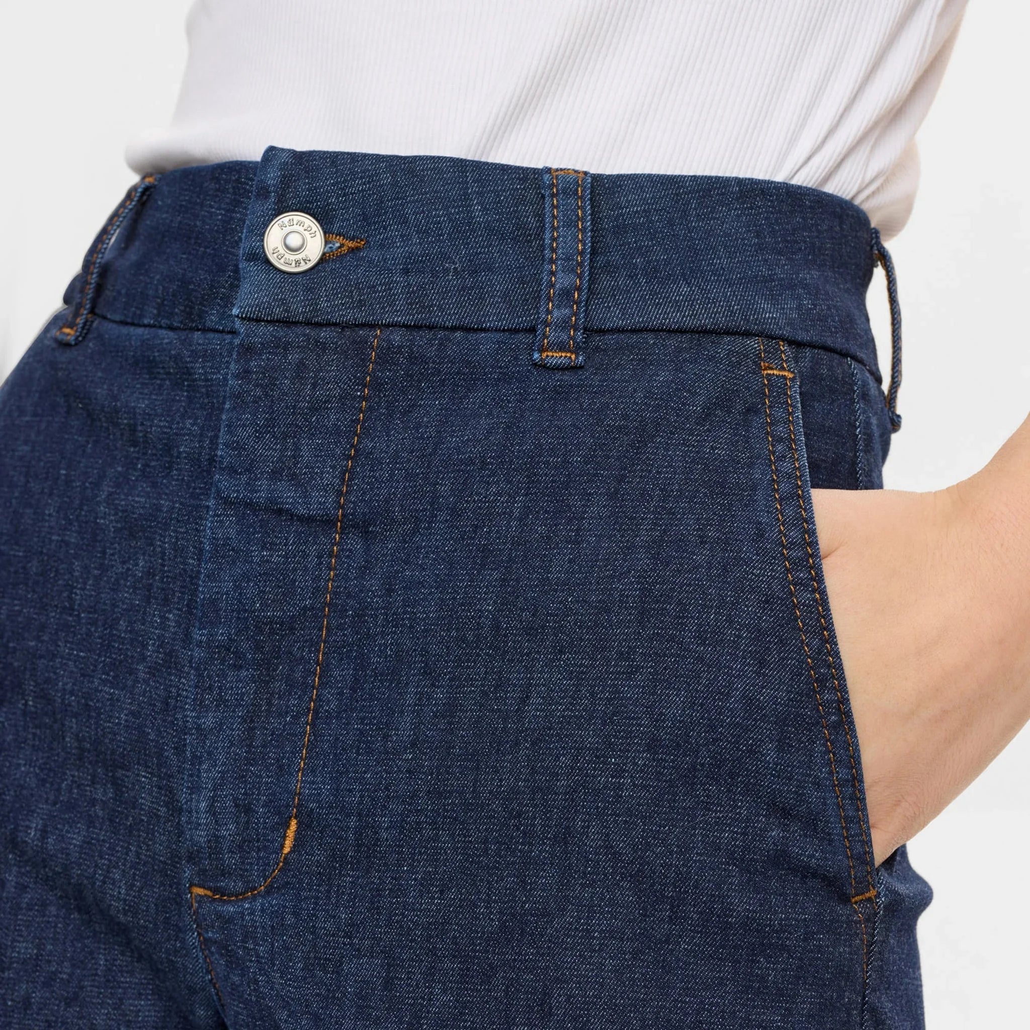 Nærbillede af knap, gylp og sidelomme på blå jeans fra Nümph med kobberfarvede syninger