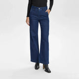 Model i mørkeblå wide leg jeans fra Nümph set forfra fra taljen og ned med sort trøje og støvletter