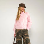 Hel figur af model i kort pink skjorte i farven Rosy Touch med camouflagebukser og brun taske