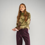 Model i grøn camouflage pullover fra Nümph stylet med bordeauxfarvede bukser, hele figuren