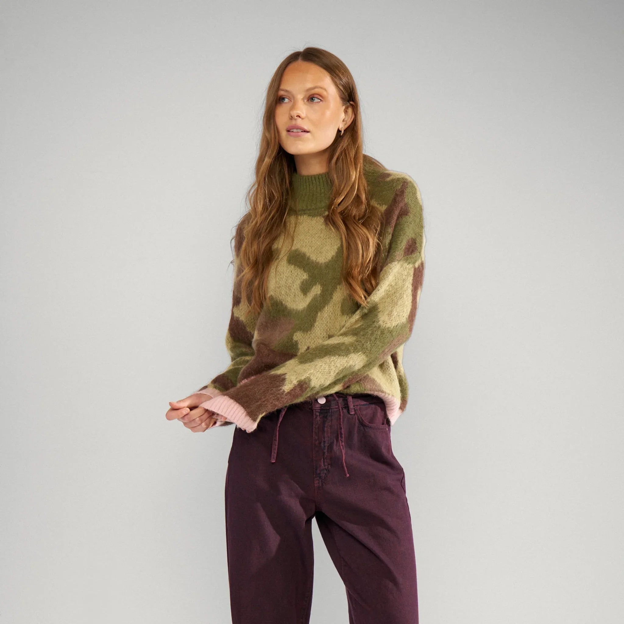 Model i grøn camouflage pullover fra Nümph stylet med bordeauxfarvede bukser, hele figuren