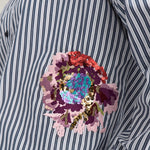 Nærbillede af broderet blomst med pailletter på stribet navy skjorte