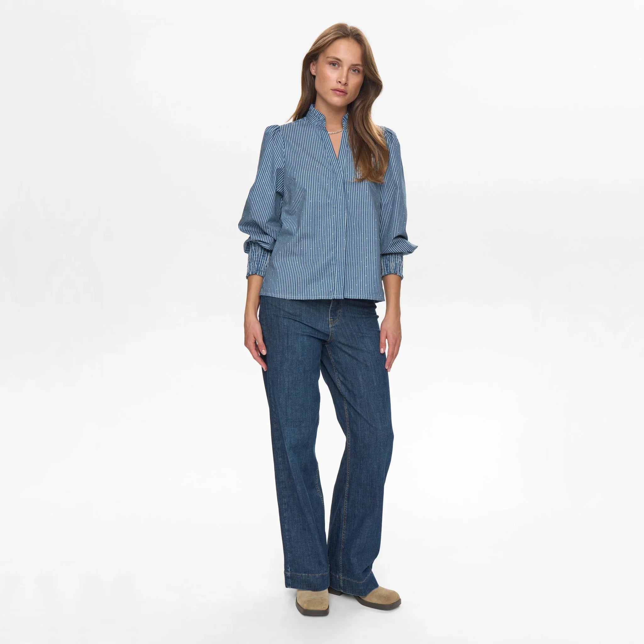 Model i fuld figur i blå stribet bluse med puffede skuldre