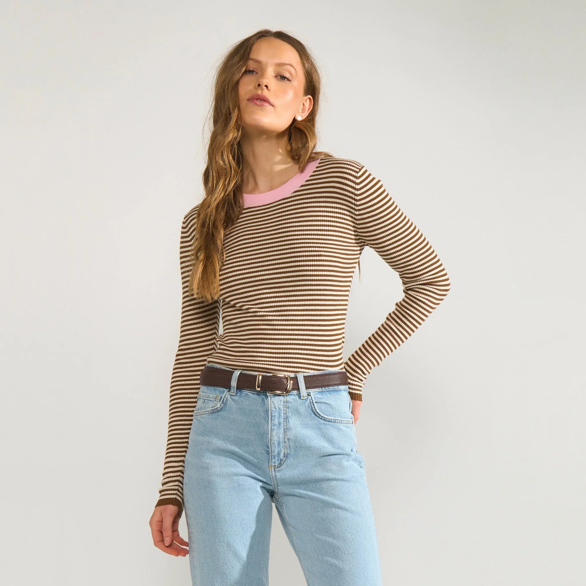 Model i brun stribet pullover med lyserød halsrib stylet med lyse jeans og brunt bælte
