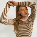 Nærbillede af stribede ærmer med brun rib og lyserød halsrib på brun pullover
