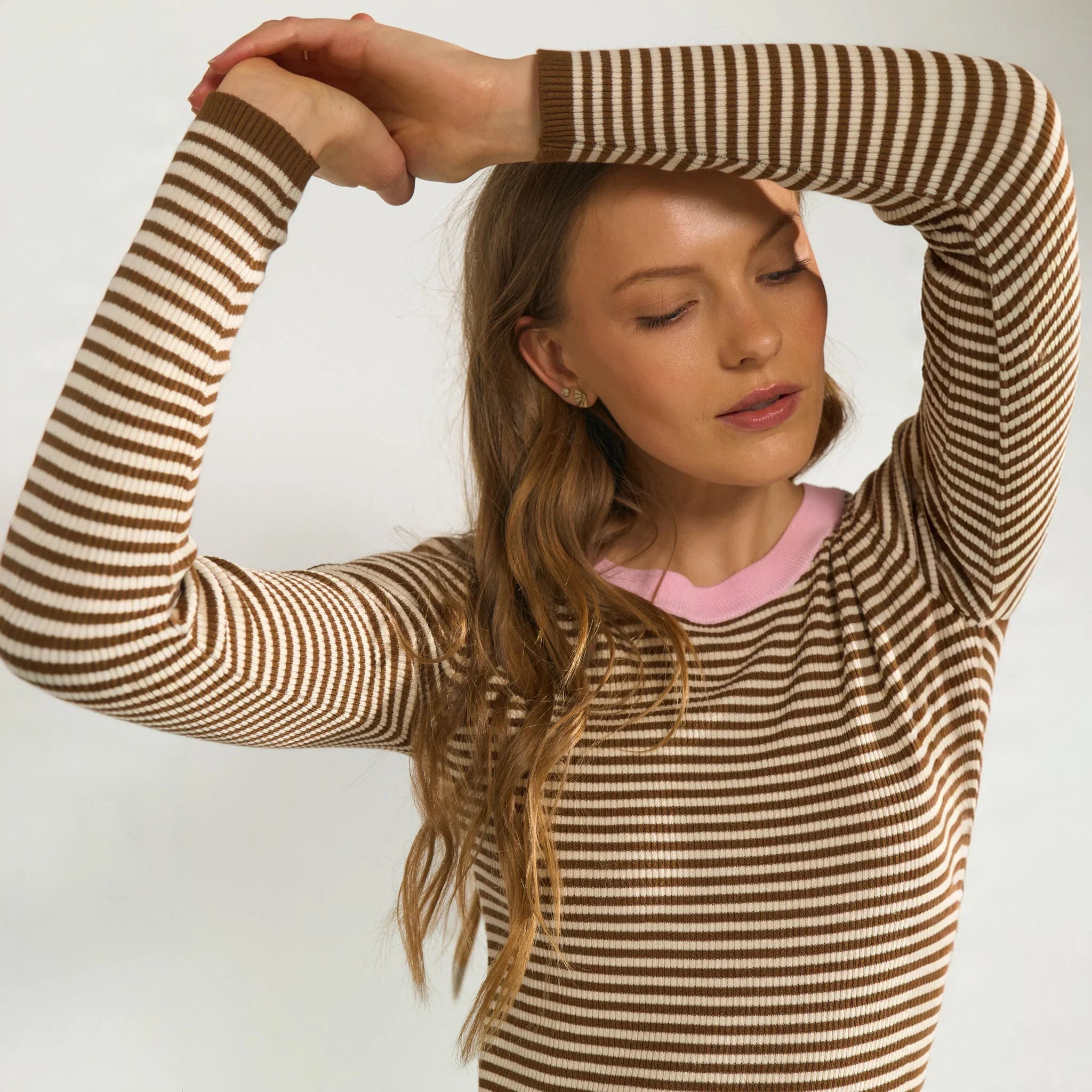 Nærbillede af stribede ærmer med brun rib og lyserød halsrib på brun pullover