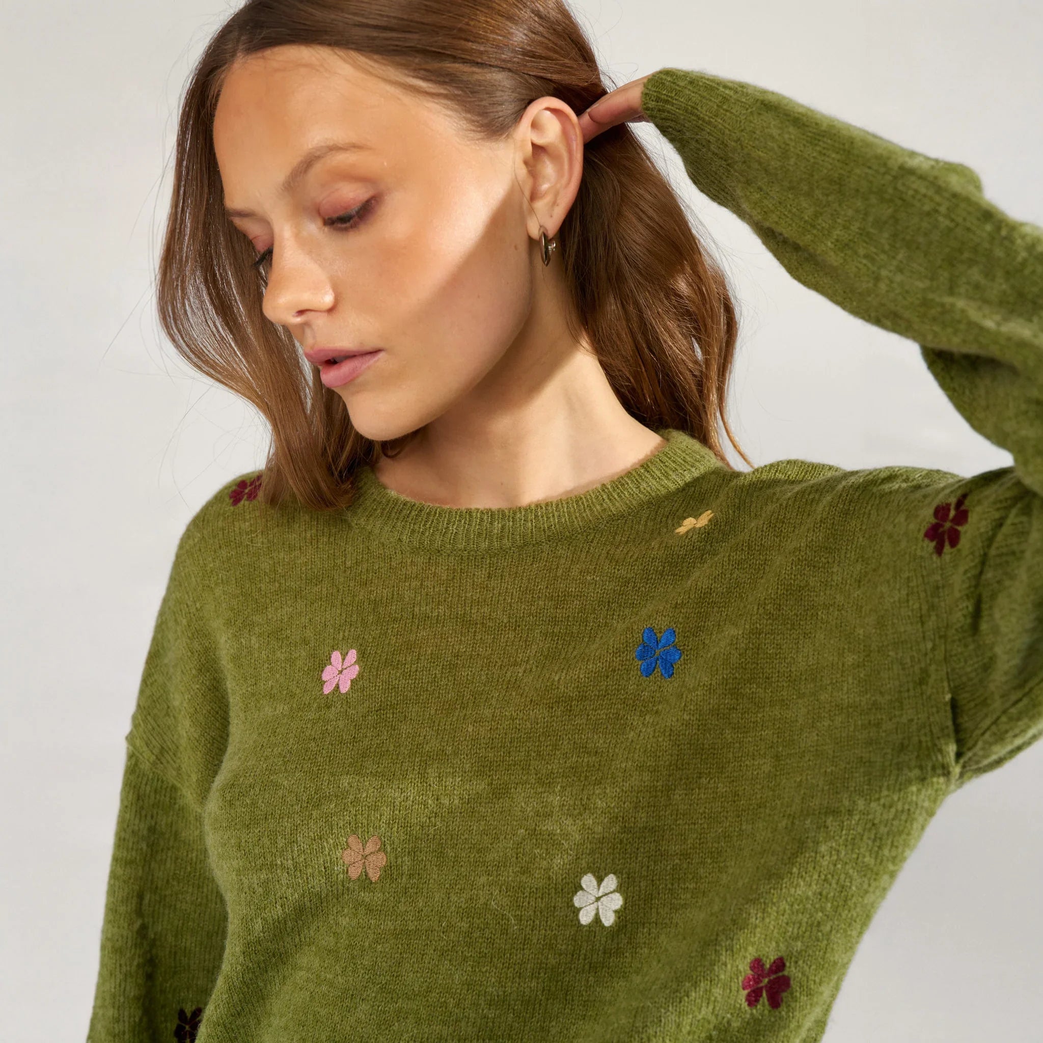 Tæt på rund hals med ribkant og broderede blomster på grøn pullover