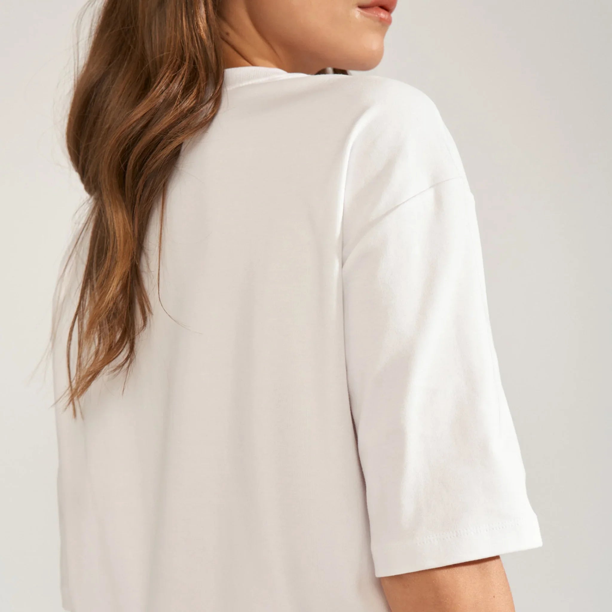Hvid t-shirt set skråt bagfra med detalje af nedfaldende skulder og ærme