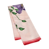 Pink satin tørklæde med blomsterprint foldet på langs, så den røde kant ses for enden