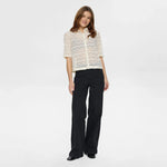 Model i hvid blondeskjorte med sorte vide jeans og sorte sko, hele figuren