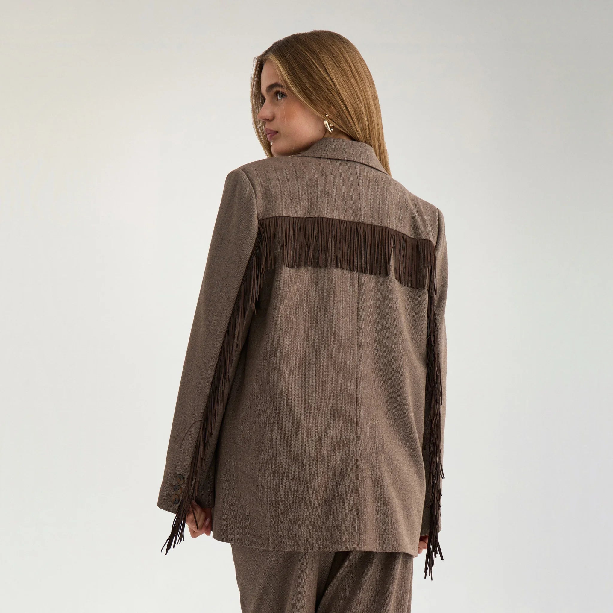 Model set bagfra i brun blazer med frynser over ryggen og langs ærmerne
