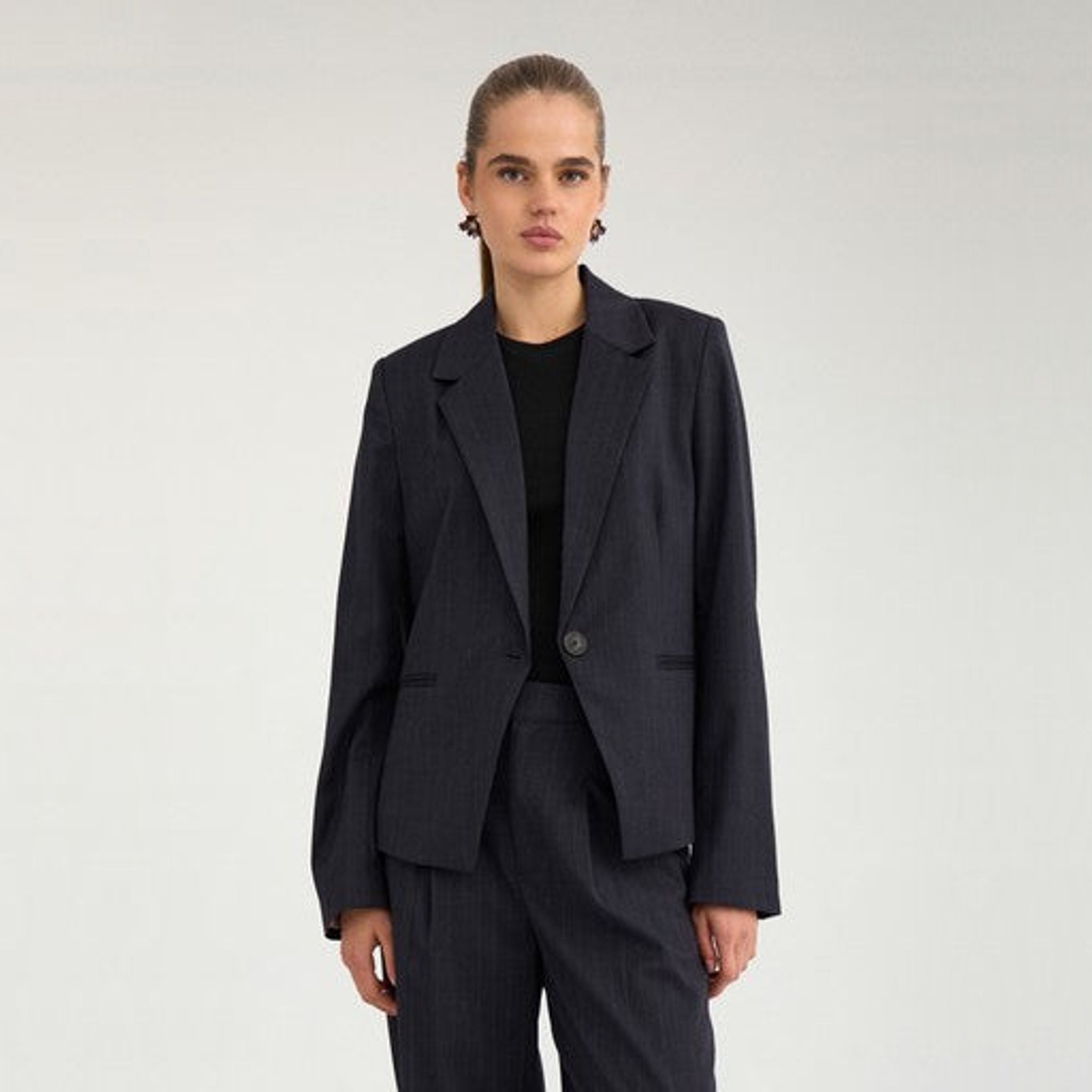 Model i navy nålestribet blazer med fitted snit over sort t-shirt, set forfra