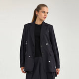 Model i navy oversize blazer med hvide motiver over en sort top, set tæt på forfra