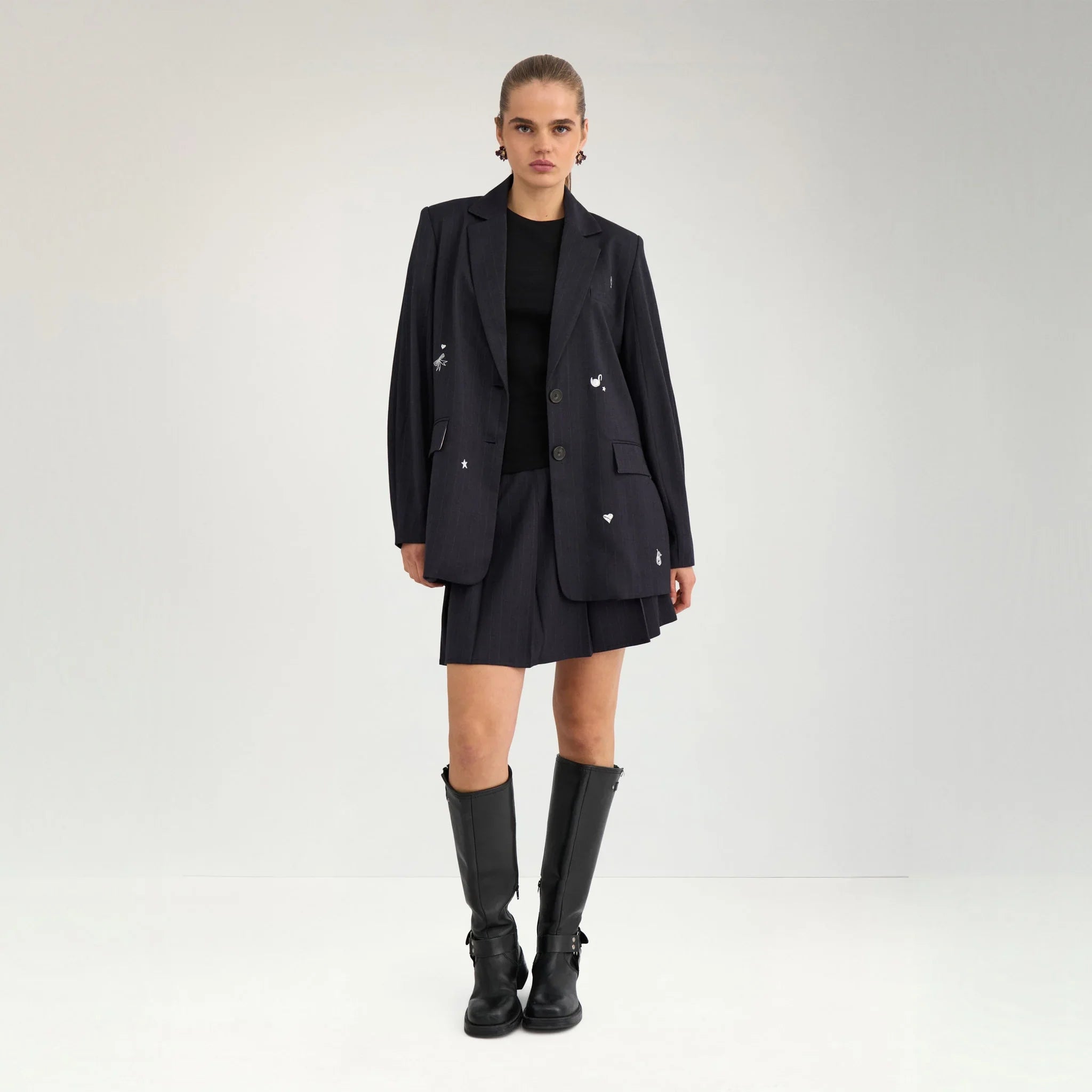 Model i navy oversize blazer med nålestriber stylet med kort nederdel og sorte støvler