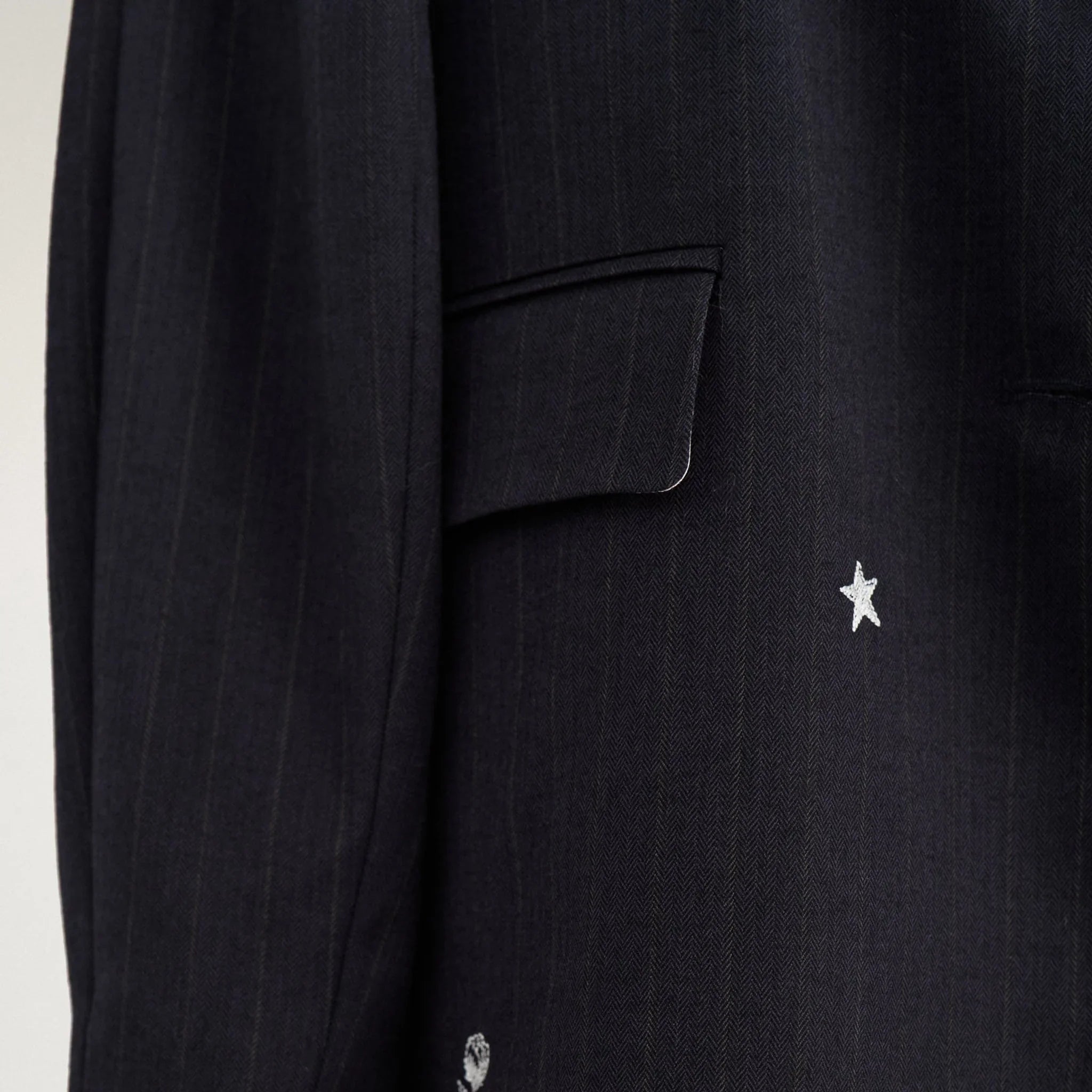 Nærbillede af lomme med klap og hvid stjerne og rose på navy nålestribet blazer