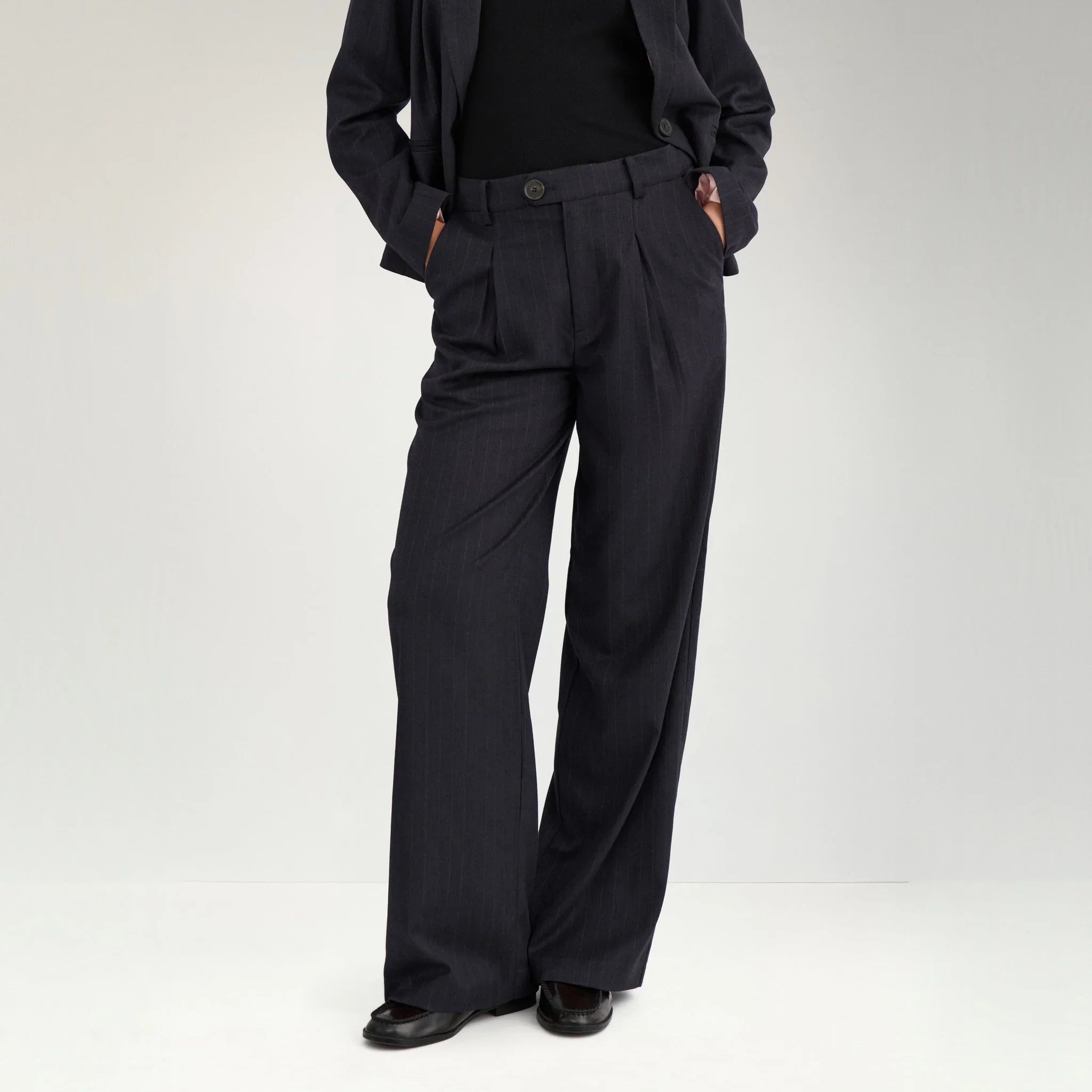 Navy wide leg bukser med nålestriber på model med hænderne i sidelommerne