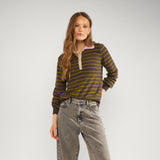 Model i hel figur i brun stribet pullover stylet med grå jeans og sorte loafers