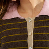 Nærbillede af lyserød polokrave og beige knapstolpe med tre knapper på brun stribet pullover