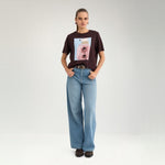 Model i fuld figur i brun t-shirt med print og lyse wide leg jeans