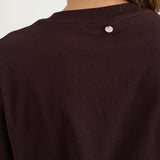 Nærbillede af lyserødt mærke i nakken på brun t-shirt i farven Chocolate Plum