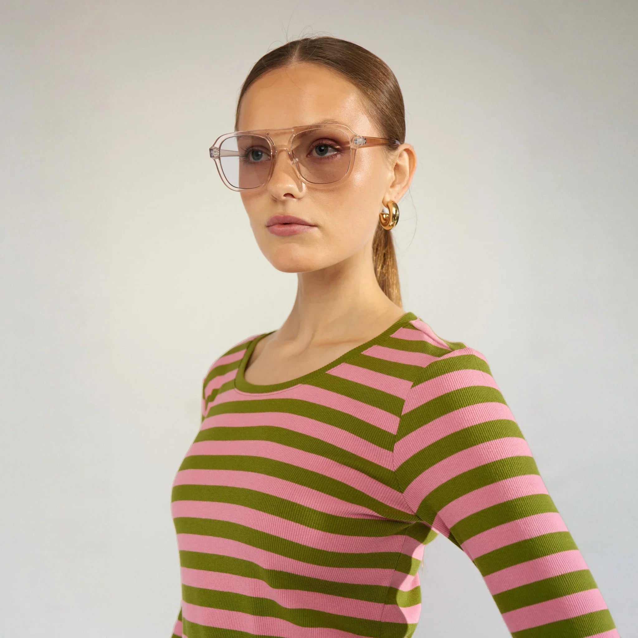 Nærbillede af rund halsudskæring på grøn og lyserød stribet bluse fra siden