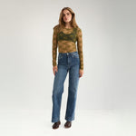 Model i grøn bluse i blonde stylet med blå wide leg jeans set i hel figur