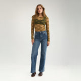Model i grøn bluse i blonde stylet med blå wide leg jeans set i hel figur