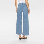 Model i lyseblå Nuparis wide leg jeans set bagfra med baglommer og bred kant forneden